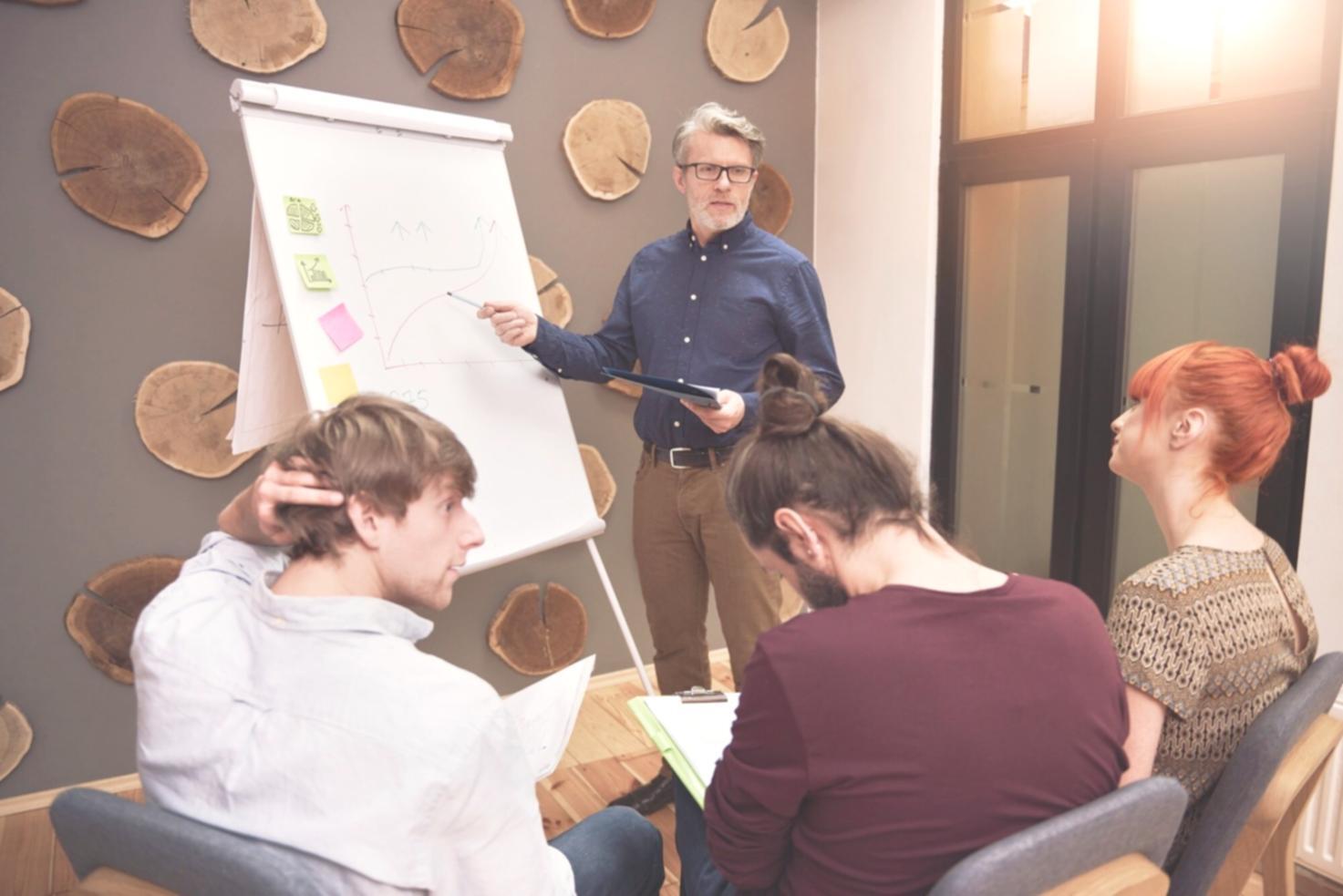 Team of analysts collaborating on market research with documents and laptops spread across conference table